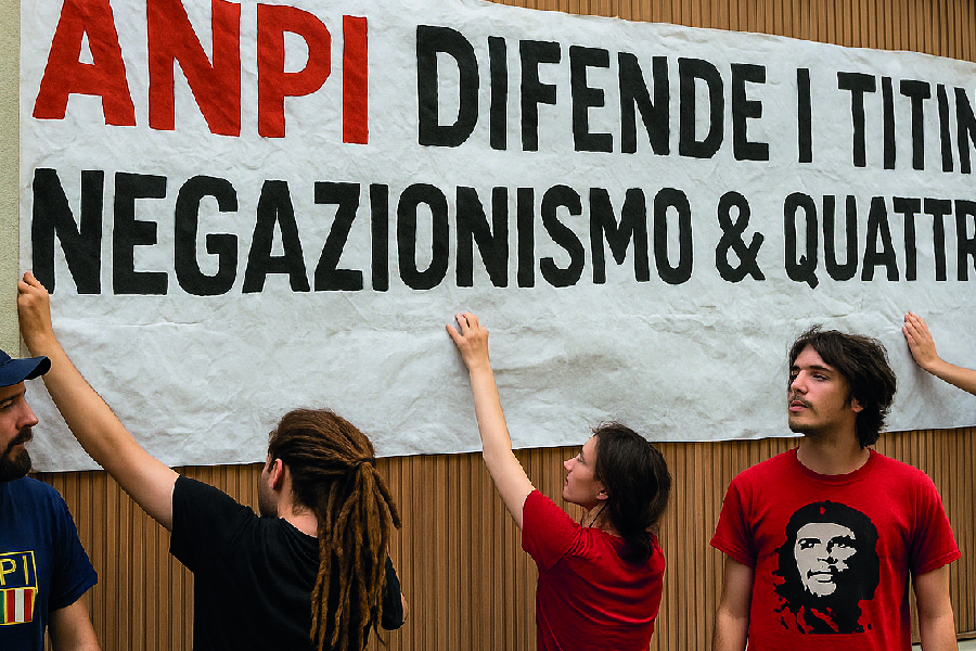 Militanti ANPI mentre appendono uno striscione firmato Casapound davanti alla loro stessa sede, tra una canna e una citazione di Che Guevara.